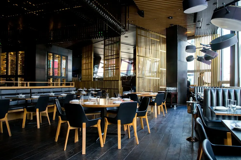 Salle chaleureuse d’une brasserie, tables dressées et lumières douces